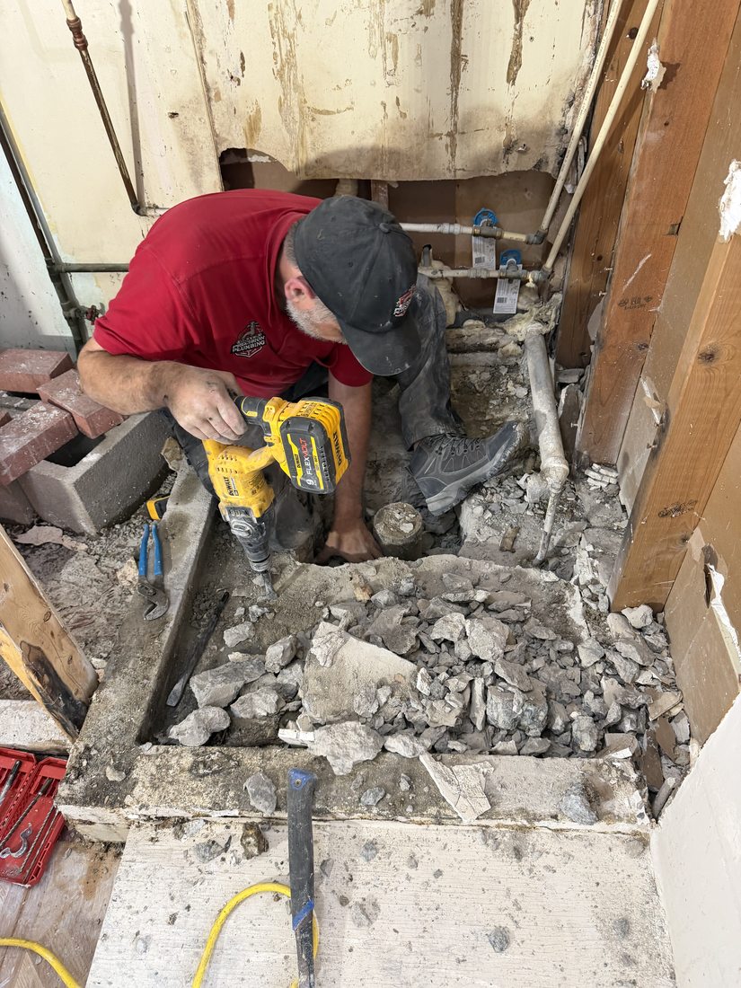 Chris Gray, Master Plumber at Gray's Precision Plumbing, drilling through concrete during a sewer line repair in Northeast Ohio
